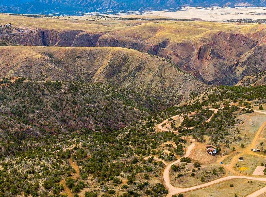 The ranch land from above, with roads winding through the pinyon hills